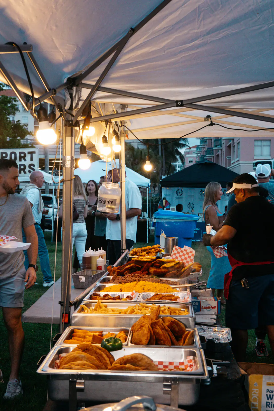 Trays of food under string lights at a vendor tent