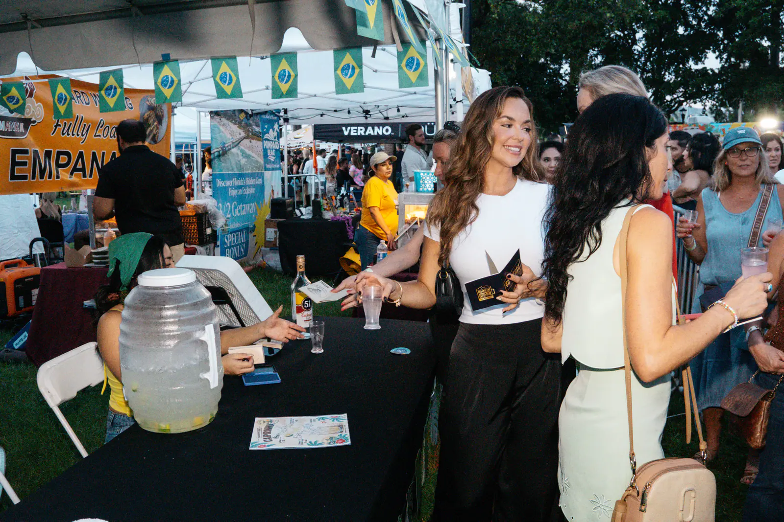 Guests with Passport Books at a tasting table beneath Brazilian flag bunting