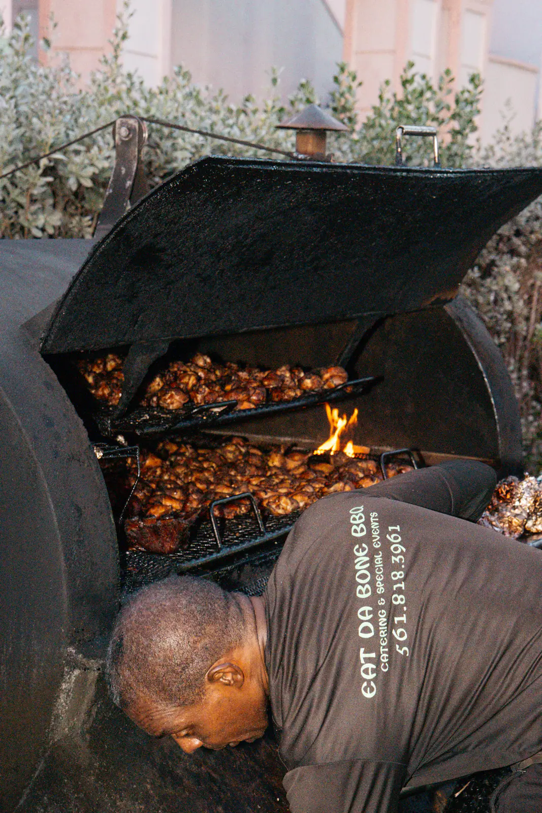 A pitmaster tending a smoker full of barbecue