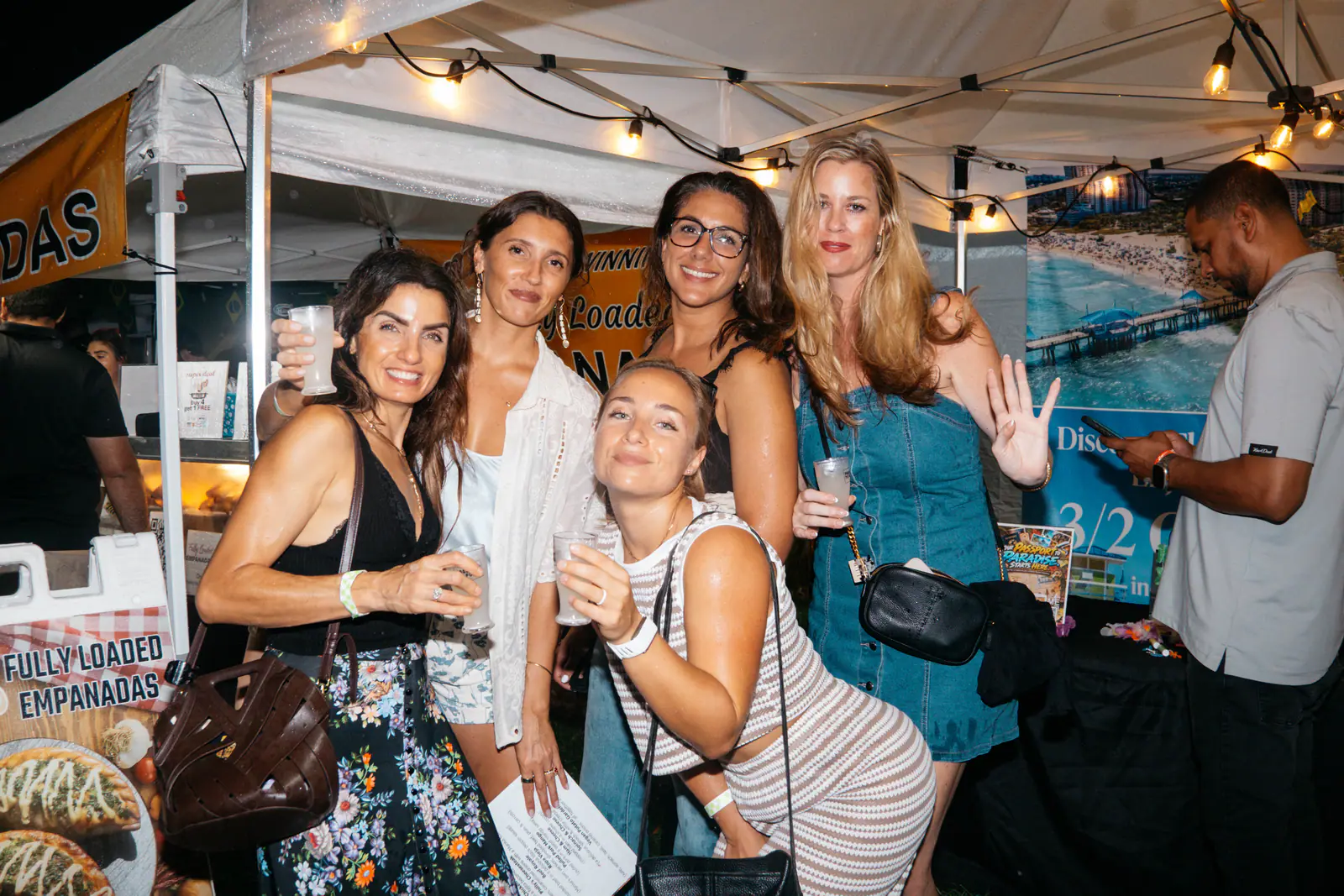 Friends with sample cups in front of a food tent