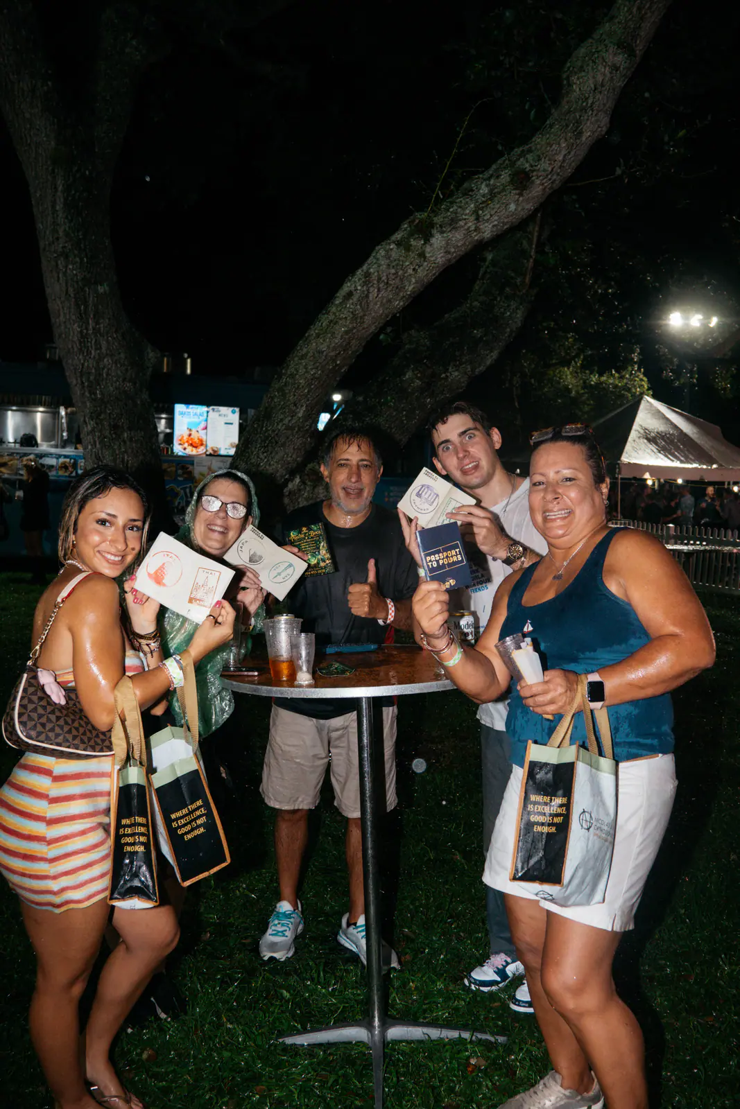 A group around a high-top table with Passport Books and tote bags