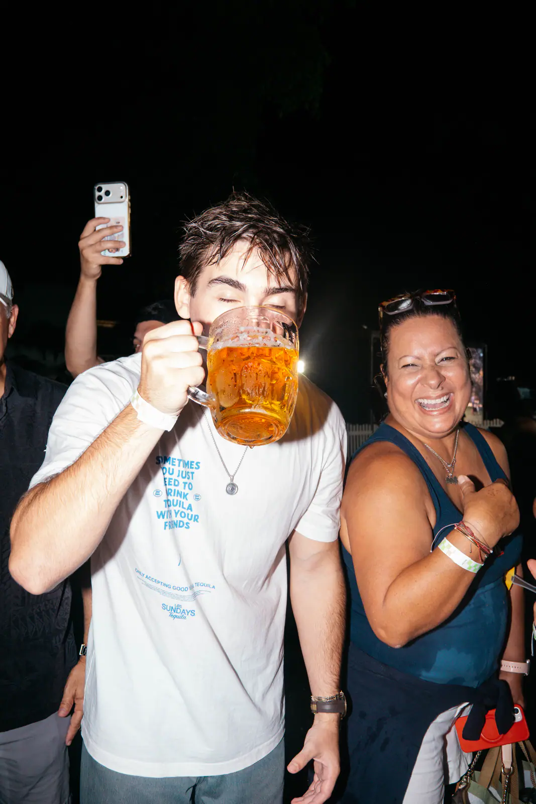 A guest drinking from a beer stein while a friend cheers