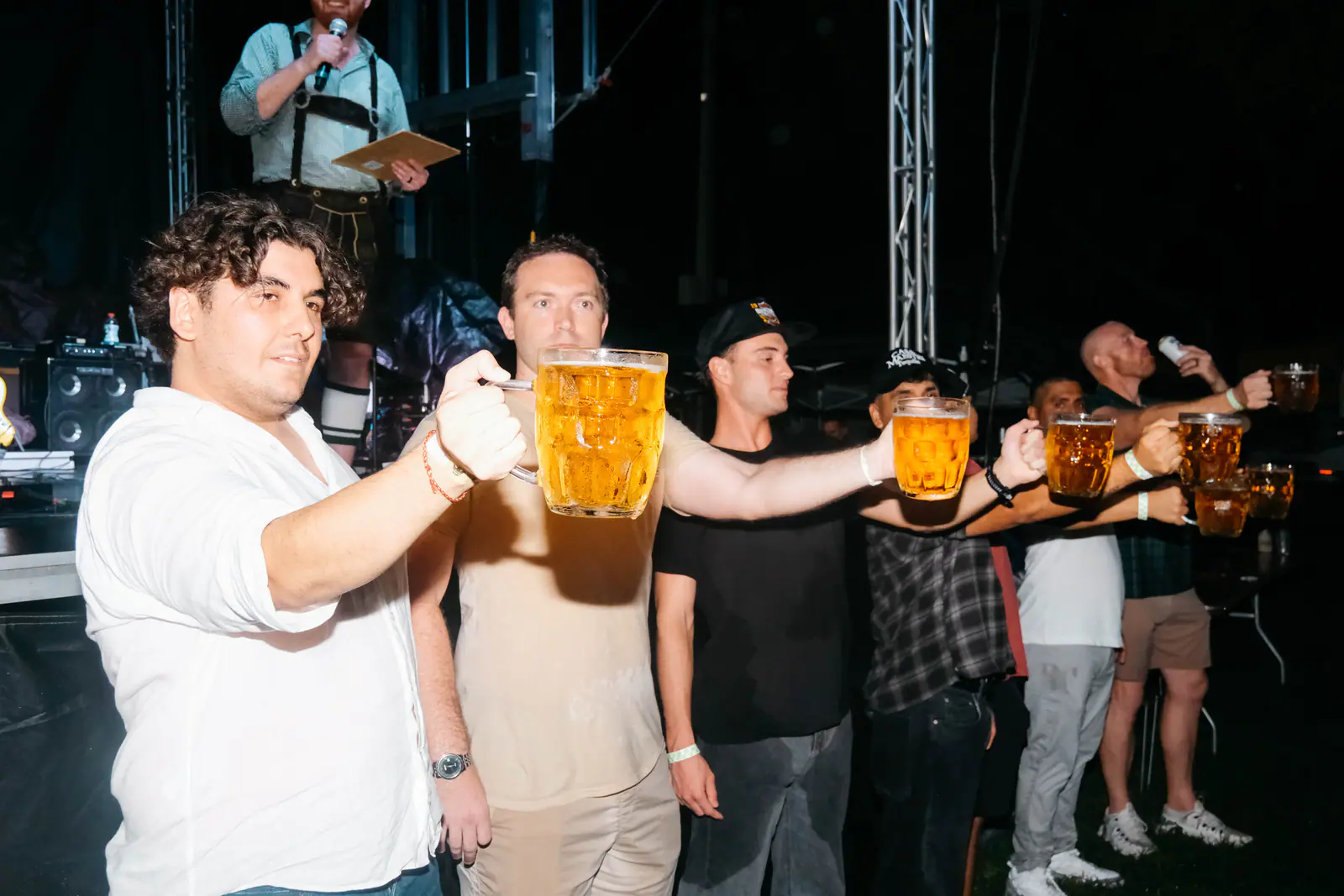 A line of guests holding beer steins at arm’s length by the stage