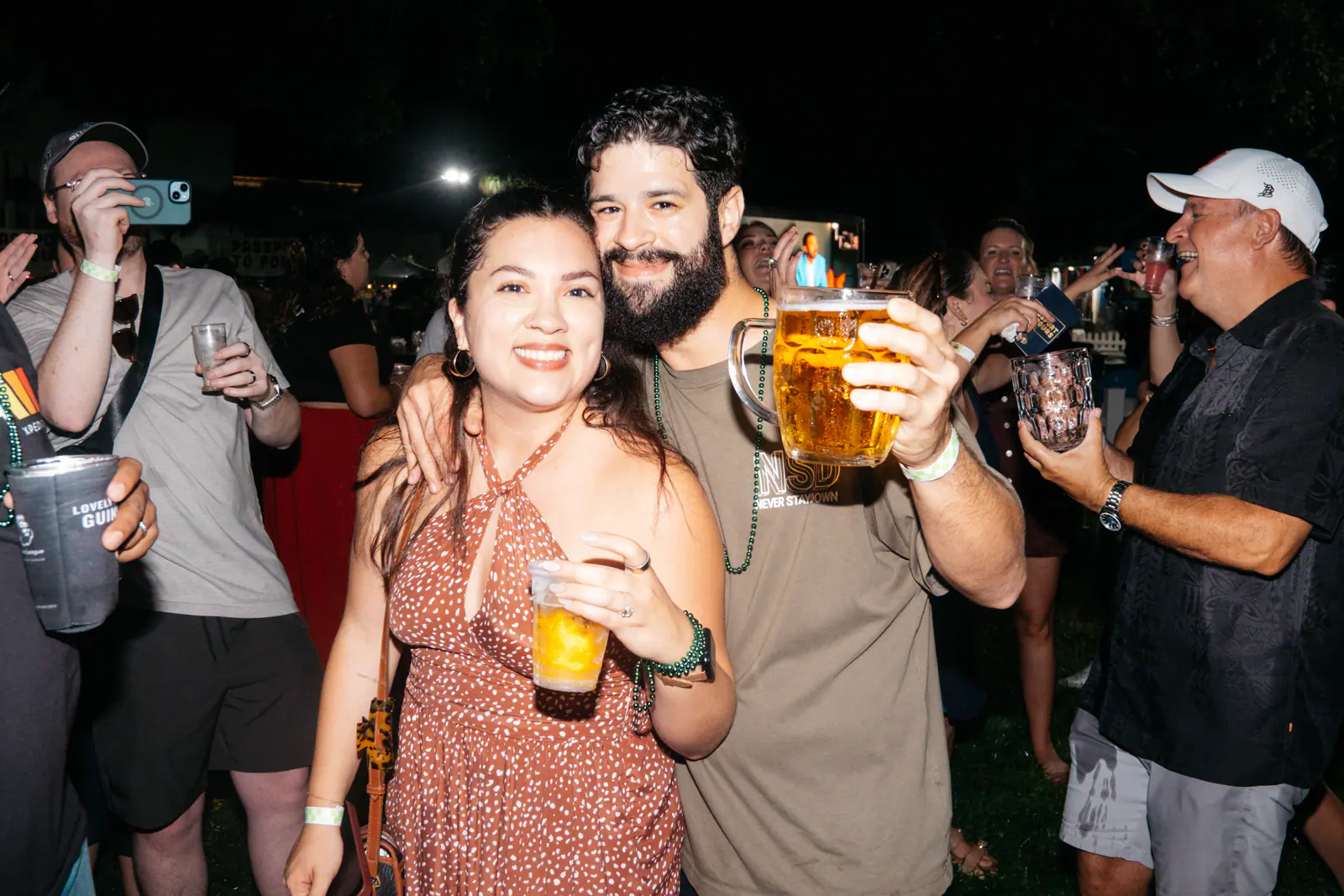 A couple posing with a beer stein in the crowd