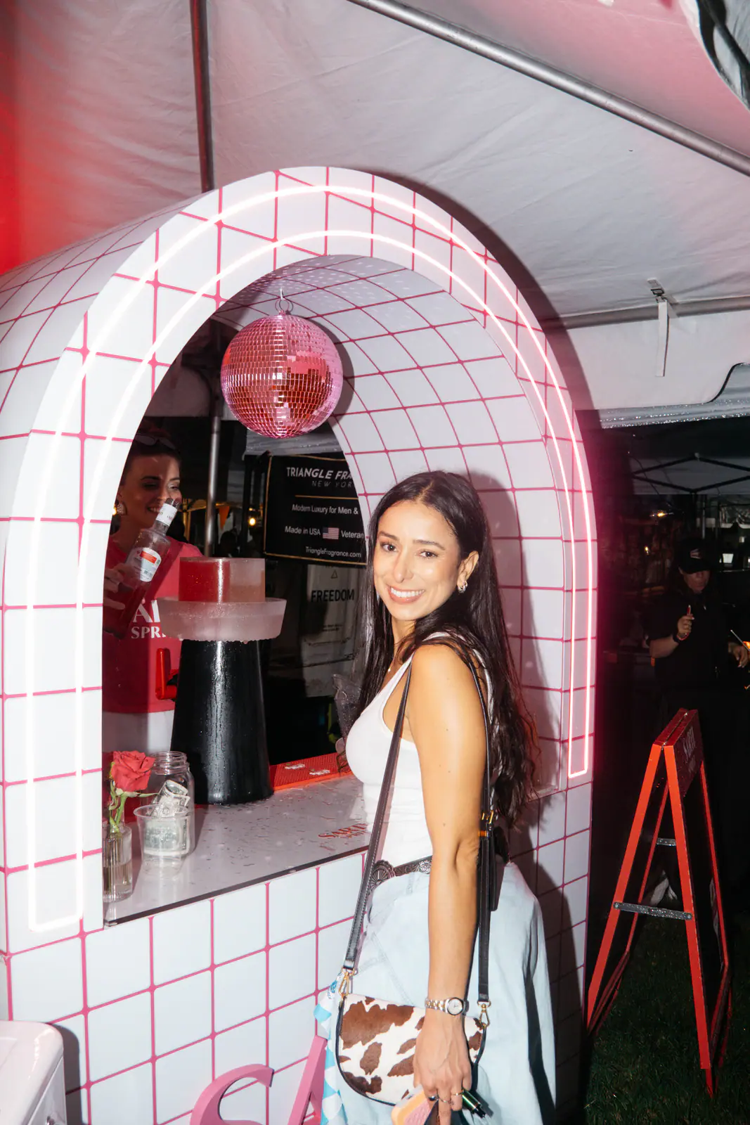 A guest posing in a pink tiled archway with a disco ball
