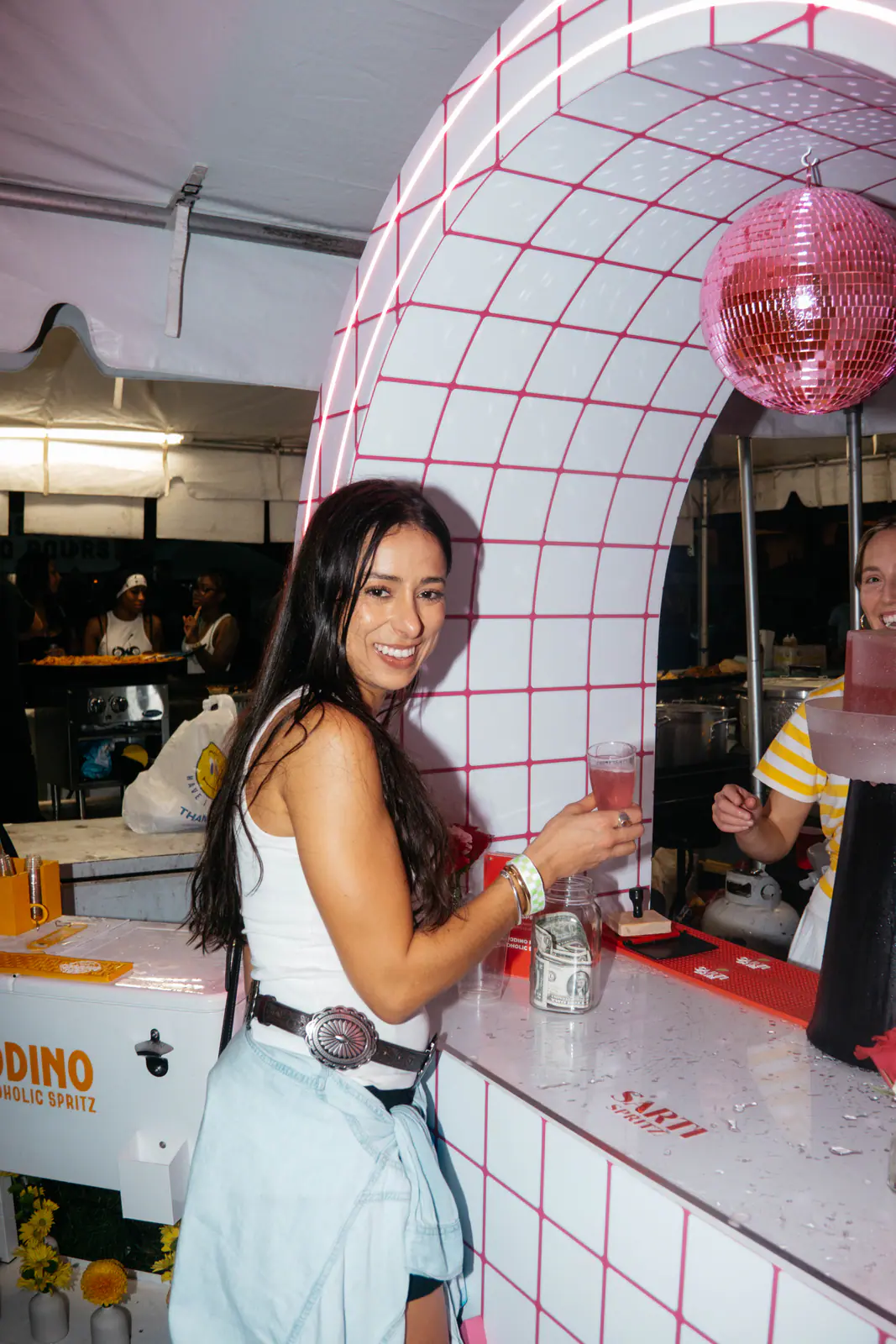 A guest at a pink tiled bar under a disco ball